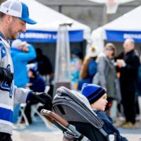 A dad wearing a GV hockey shirt pushes a strolling with two little Lakers